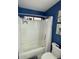 Bathroom with blue walls, white bathtub with shower, and white tiled walls at 135 S Abalone Dr, Gilbert, AZ 85233