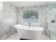 Stylish bathroom featuring a modern freestanding tub, marble tiled walls, and a large window at 1532 W Northern Ave, Phoenix, AZ 85021