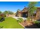 Spacious backyard featuring artificial turf, mature desert landscaping, and a covered patio at 15422 W Ventura St, Surprise, AZ 85379