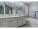 Bathroom featuring a double vanity with granite counters, large mirror, and separate tub and walk-in shower at 15422 W Ventura St, Surprise, AZ 85379
