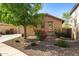 Inviting home exterior with low-maintenance desert landscaping and a mature tree providing shade at 15422 W Ventura St, Surprise, AZ 85379