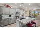 Bright kitchen with a large island featuring light countertops and gray cabinetry, open to dining area with backyard access at 15422 W Ventura St, Surprise, AZ 85379