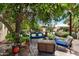 Lush backyard with a blue bench and chairs under a shade tree for relaxing at 1656 W Meseto Cir, Mesa, AZ 85202