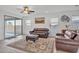 Bright living room with leather couches, a ceiling fan, an area rug, and plenty of natural light at 18100 W College Dr, Goodyear, AZ 85395