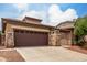 Home exterior with stone accents on garage and entry pillars with a large driveway and well-kept yard at 18719 E Pelican Ct, Queen Creek, AZ 85142