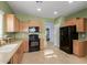 Well-lit kitchen featuring black appliances, tile flooring, and light wood cabinets at 19667 N 260Th N Ln, Buckeye, AZ 85396