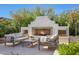 Beautiful outdoor fireplace with seating area, firewood storage, and lush landscaping for luxurious outdoor living at 20510 W White Rock Rd, Buckeye, AZ 85396