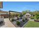 Inviting outdoor living area featuring a fireplace, pergola, and lush landscaping at 20510 W White Rock Rd, Buckeye, AZ 85396