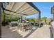 Backyard featuring a pergola-covered dining area, fireplace, and lush landscaping, ideal for entertaining at 20510 W White Rock Rd, Buckeye, AZ 85396