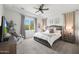 Bright main bedroom featuring a large window, tray ceiling, ceiling fan, and plush carpeting at 20510 W White Rock Rd, Buckeye, AZ 85396