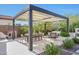 Outdoor dining area under a pergola, surrounded by lush landscaping in a private backyard setting at 20510 W White Rock Rd, Buckeye, AZ 85396