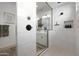 Glass enclosed shower with white tile walls, black hardware, and small window at 20510 W White Rock Rd, Buckeye, AZ 85396