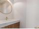 Stylish powder room featuring a round mirror, stone countertop, and wood cabinetry at 20929 N 37Th Way, Phoenix, AZ 85050