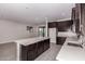 Open-concept kitchen with dark cabinets, stainless steel appliances, a center island, and wood-look tile at 22895 N 183Rd Dr, Surprise, AZ 85387