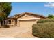 Single story home with two car garage, desert landscaping and mature green shrubs at 2590 S Buckaroo Trl, Gilbert, AZ 85295