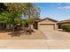Charming single-story home with a two car garage, desert landscaping, and mature shade trees at 2590 S Buckaroo Trl, Gilbert, AZ 85295