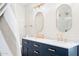 Bright bathroom with dual sinks, navy vanity, gold fixtures, and modern oval mirrors at 35360 N 93Rd Way, Scottsdale, AZ 85262