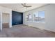 Stylish bedroom featuring a striking accent wall, large windows, and a modern ceiling fan at 41251 W Barcelona Dr, Maricopa, AZ 85138