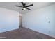 Bright bedroom with neutral carpet, ceiling fan, and an open doorway leading to another room at 41251 W Barcelona Dr, Maricopa, AZ 85138