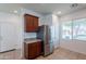 Well-lit kitchen featuring stainless steel refrigerator, neutral stone countertops and dark wood cabinets at 41251 W Barcelona Dr, Maricopa, AZ 85138
