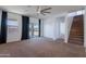 Inviting living space featuring a ceiling fan, large windows, and access to the outdoor area and staircase at 41251 W Barcelona Dr, Maricopa, AZ 85138