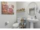 Simple bathroom with a pedestal sink, modern toilet, and decorative artwork on the walls at 6305 W Pleasant Oak Ct, Florence, AZ 85132