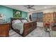 Comfortable bedroom featuring a wooden bed frame, ceiling fan, and teal accent wall with peacock art at 6305 W Pleasant Oak Ct, Florence, AZ 85132