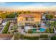 Aerial view of the property's backyard featuring a pool, patio, lush landscaping, and mature trees at 8500 W Nicolet Ave, Glendale, AZ 85305