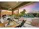 Covered patio with a view of the pool, waterfall, and landscaping at sunset at 8500 W Nicolet Ave, Glendale, AZ 85305