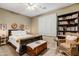 Cozy bedroom featuring a queen bed, ceiling fan, and built-in bookcase filled with books at 8500 W Nicolet Ave, Glendale, AZ 85305