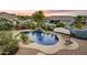 Resort-style backyard featuring a sparkling pool, waterfall feature, lush landscaping, and ample seating at 8500 W Nicolet Ave, Glendale, AZ 85305