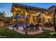 Covered patio with dining area and outdoor string lights overlooking the pool at 1015 E Constitution Dr, Gilbert, AZ 85296