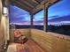 Relaxing covered balcony with views of the city lights below and a comfortable wicker chair at 10287 E Diamond Rim Dr, Scottsdale, AZ 85255