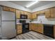 Functional kitchen featuring stainless steel refrigerator, black appliances, wood cabinets, and modern flooring at 1050 S Stapley Dr # 62, Mesa, AZ 85204