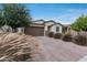 Charming single-story home boasts a brown garage door, brick-paved driveway and front yard landscaping at 11574 W Luxton Ln, Avondale, AZ 85323