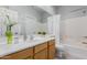 Bright bathroom with white countertop, wood cabinets and bathtub with shower at 1351 N Pleasant Dr # 2051, Chandler, AZ 85225