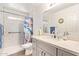 Bright bathroom showcasing a modern vanity with a marble countertop and shower with patterned tile and a beach-themed curtain at 14390 W Morning Star Trl, Surprise, AZ 85374