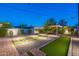 Backyard featuring a bocce ball court, lush landscaping with professional lighting and a covered seating area with fire pit at 1513 E Sheridan St, Phoenix, AZ 85006