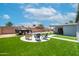 View of a landscaped backyard with artificial turf, a firepit area, patio, outbuilding and trailer at 1531 S Padre Rd, Apache Junction, AZ 85119