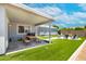 Charming covered patio with a picnic table and an artificial grass backyard with a swing and sitting area under a sunny blue sky at 1531 S Padre Rd, Apache Junction, AZ 85119