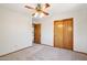 A simple bedroom features neutral carpet, ceiling fan, and double-door closet at 1813 E Sheena Dr, Phoenix, AZ 85022