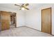 Bright bedroom with neutral carpet, ceiling fan, and wood-trimmed doorway and closet at 1813 E Sheena Dr, Phoenix, AZ 85022