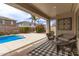 Covered patio overlooking a pool, complemented by a seating area and landscaped backyard with a privacy fence at 18614 E Oriole Way, Queen Creek, AZ 85142
