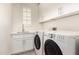 Bright laundry room with modern washer and dryer, white cabinets, sink, and a window with plantation shutters at 18614 E Oriole Way, Queen Creek, AZ 85142