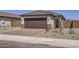 Contemporary home featuring a two-car garage, decorative stone accents, and brick paver driveway at 25109 N 174Th Ln, Surprise, AZ 85387