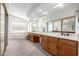 Bright bathroom featuring a long vanity with wood cabinets, a large mirror and soaking tub by the window at 3337 E Glade Cir, Mesa, AZ 85204
