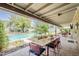 Covered patio area with outdoor dining, overlooking a backyard pool and verdant landscaping at 402 E Claremont St, Phoenix, AZ 85012