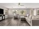 Spacious living room featuring neutral walls, wood floors, and large windows with modern ceiling fan at 4142 E Sandy Way, Gilbert, AZ 85297