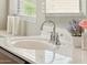 Close-up of a bathroom sink with a chrome faucet, decorative accents, and a view through the window at 43884 W Kramer Ln, Maricopa, AZ 85138