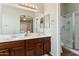 Bathroom vanity with double sinks, a large mirror, and a shower with a glass door at 43884 W Kramer Ln, Maricopa, AZ 85138
